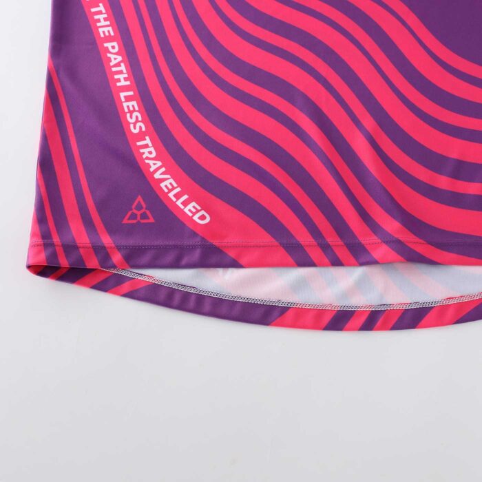 Close up of the bottom edge of a pink and purple cycling top showing stitching
