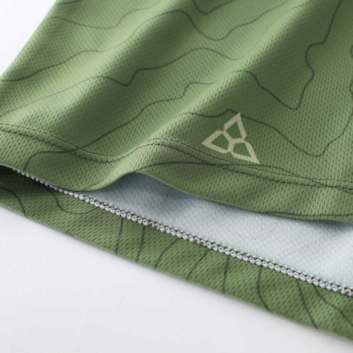 Close up shot showing the good quality of the stitching detail on the hem of a green cycling top