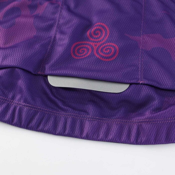 Close up of a reflective tab on the botrear hem of a purple cycling top